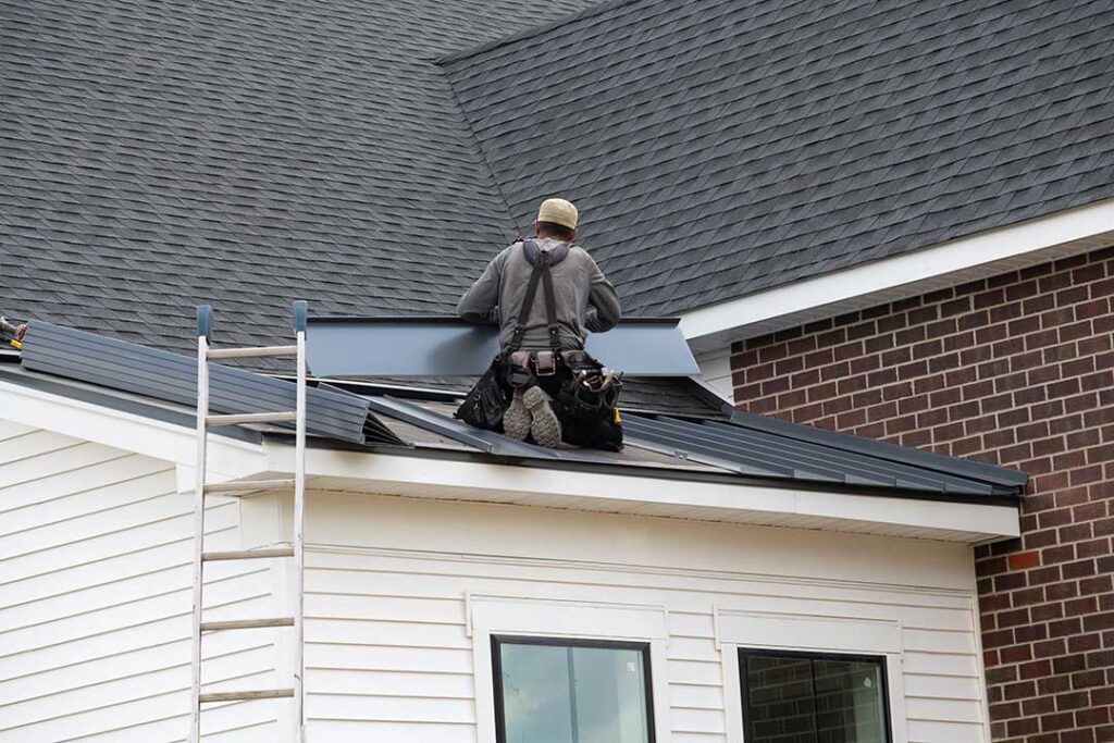 Solar panels mounted on a residential shingle roof with snow nearby and a roof inspection underway.