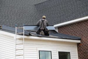 Solar panels mounted on a residential shingle roof with snow nearby and a roof inspection underway.